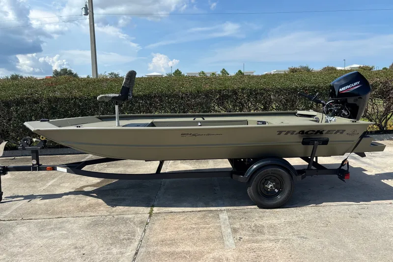 The Image of 2027 Tracker Grizzly 1654 T Sportsman boat on trailer, featuring Mercury outboard motor. - 0