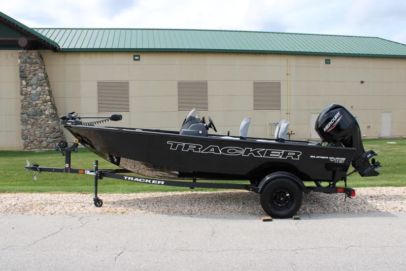 The Image of 2027 Tracker Super Guide V-16 SC boat on trailer, parked outdoors. - 0