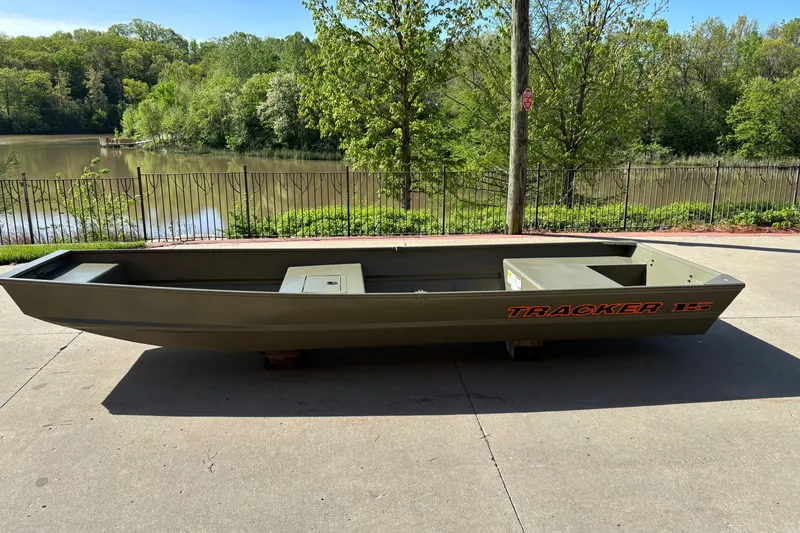 The Image of 2027 Tracker Grizzly 15 Jon boat on concrete near a scenic lake. - 0