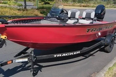 The Image of Red 2027 Tracker Super Guide V-16 SC boat on trailer, parked outdoors. - 0