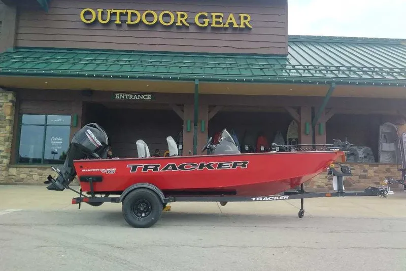 The Image of Red 2027 Tracker Super Guide V-16 SC boat on trailer outside outdoor gear store. - 0