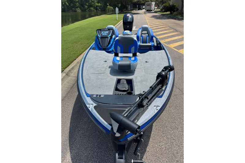 Slide: The Image of 2027 Nitro Z18 XL boat with blue seats, parked near a lake. - 9