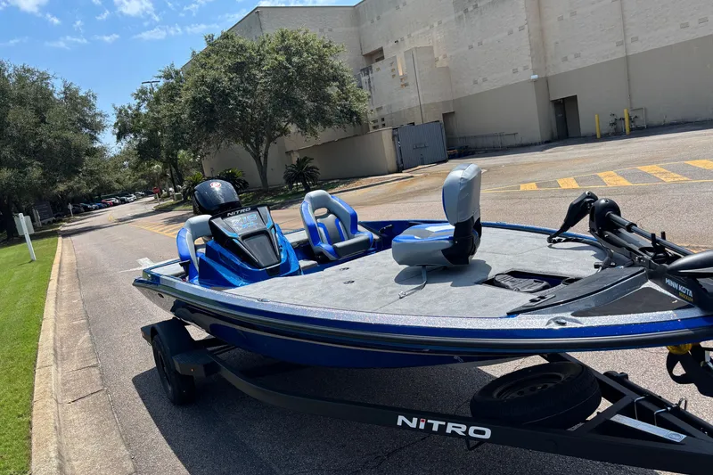 Slide: The Image of 2027 Nitro Z18 XL boat on trailer, parked on a sunny street near trees and buildings. - 7