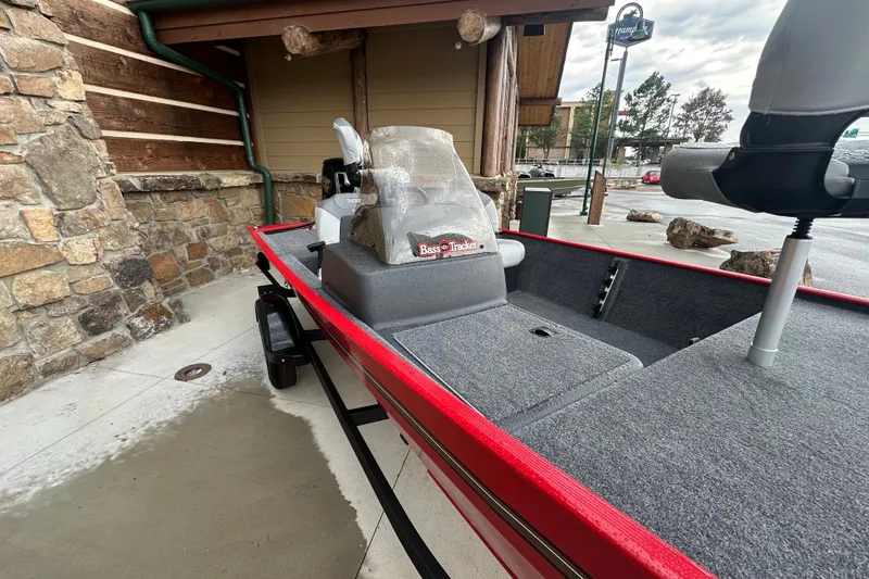 Slide: The Image of 2027 Tracker Bass Tracker Classic XL boat with red trim, parked near a rustic building. - 60