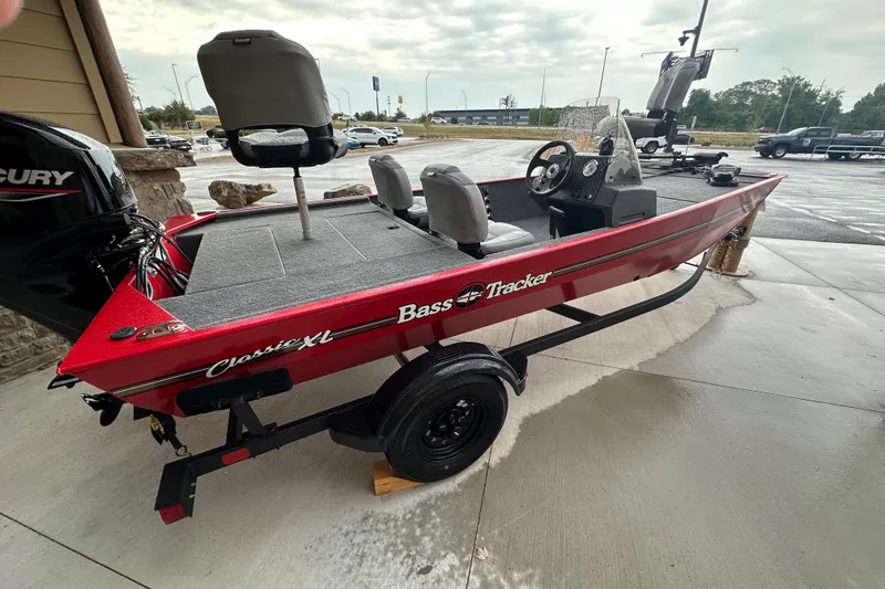 The Image of 2027 Tracker Bass Tracker Classic XL boat on trailer, red exterior, parked outdoors. - 0