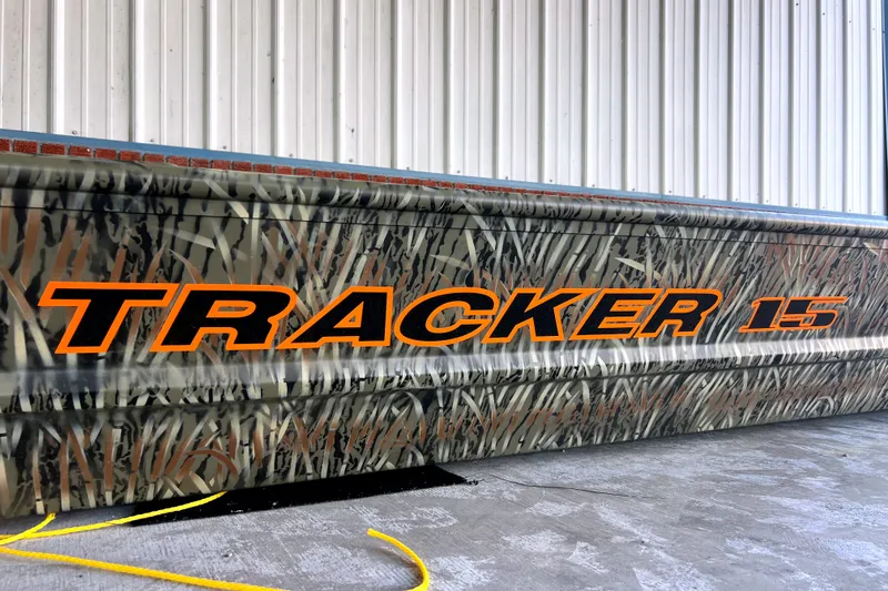 The Image of 2027 Tracker Grizzly 15 Jon boat with camouflage design and bold orange lettering. - 0