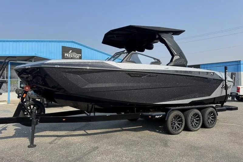 Slide: The Image of 2027 Tigé 25ZX boat on trailer, sleek black design, parked outside Prestige dealership. - 18