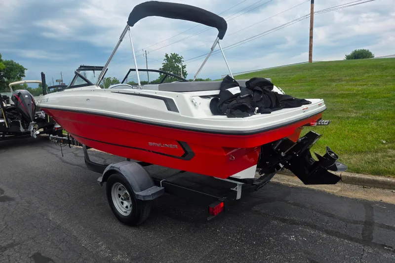 Slide: The Image of 2022 Bayliner VR4 Bowrider I/O boat on trailer, red and white design, parked outdoors. - 3