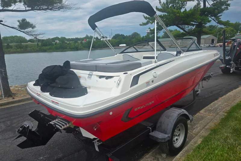 Slide: The Image of 2022 Bayliner VR4 Bowrider I/O boat on trailer by a lakeside road. - 1
