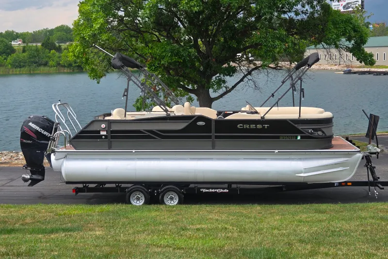 The Image of 2016 Crest Classic 230 Chateau pontoon boat on trailer by a lake. - 0