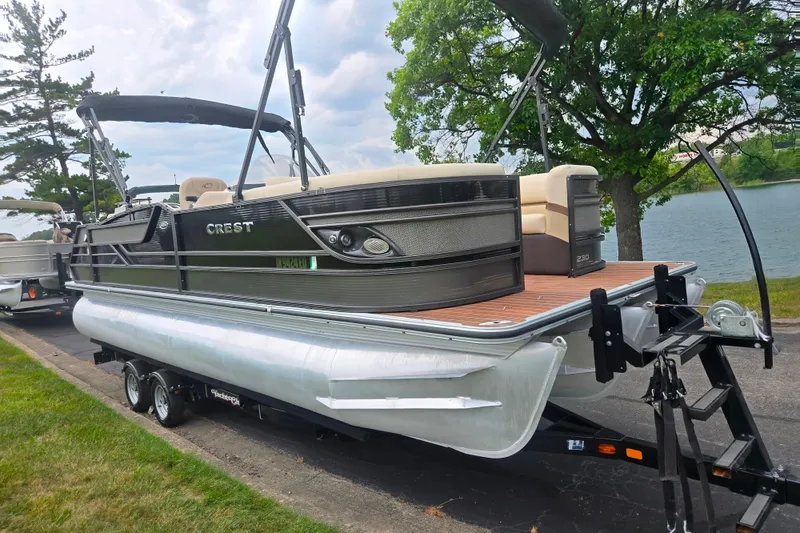 Slide: The Image of 2016 Crest Classic 230 Chateau pontoon boat on trailer by a lake. - 8