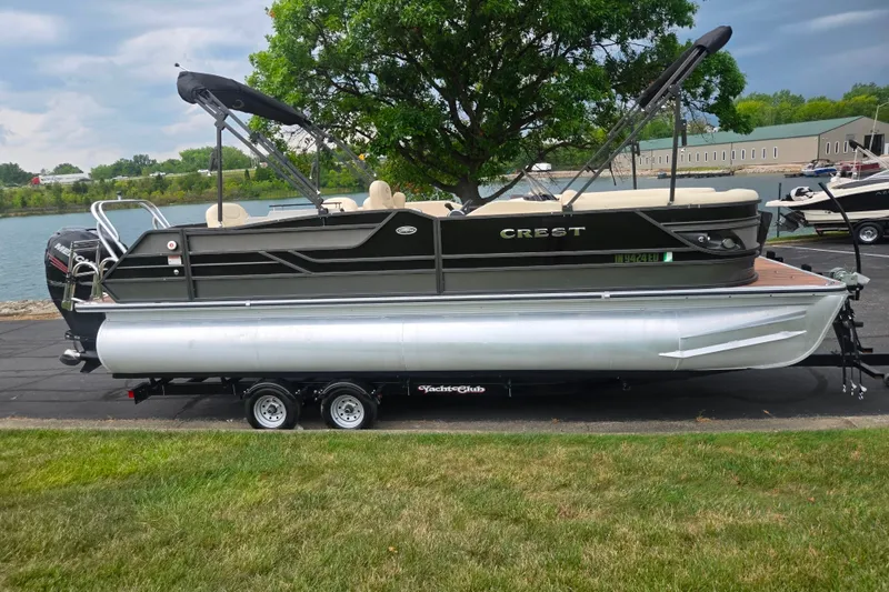 Slide: The Image of 2016 Crest Classic 230 Chateau pontoon boat on trailer by a lake. - 9