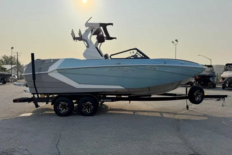 Slide: The Image of 2027 Supra R225 boat on trailer, parked outdoors under a hazy sky. - 12