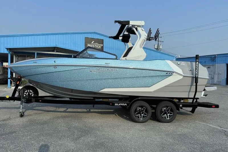Slide: The Image of 2027 Supra R225 boat on trailer, parked outside a blue building. - 16
