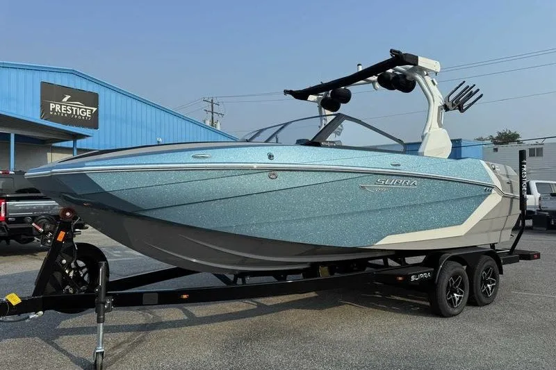 The Image of 2027 Supra R225 boat on trailer at dealership, featuring sleek blue design. - 0