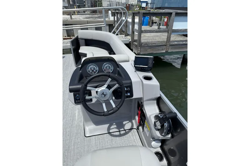 Slide: The Image of 2025 Harris Cruiser 230 boat dashboard with steering wheel and control panel at dock. - 8
