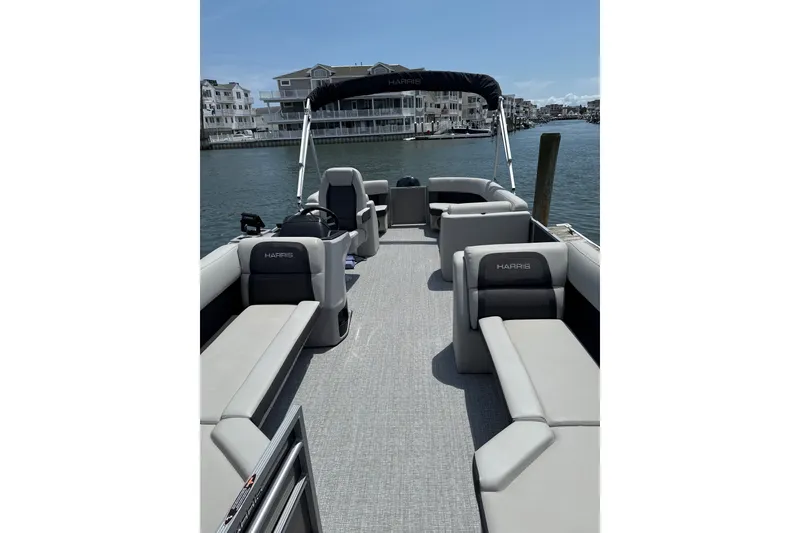 Slide: The Image of 2025 Harris Cruiser 230 pontoon boat with spacious seating on a sunny waterfront. - 4