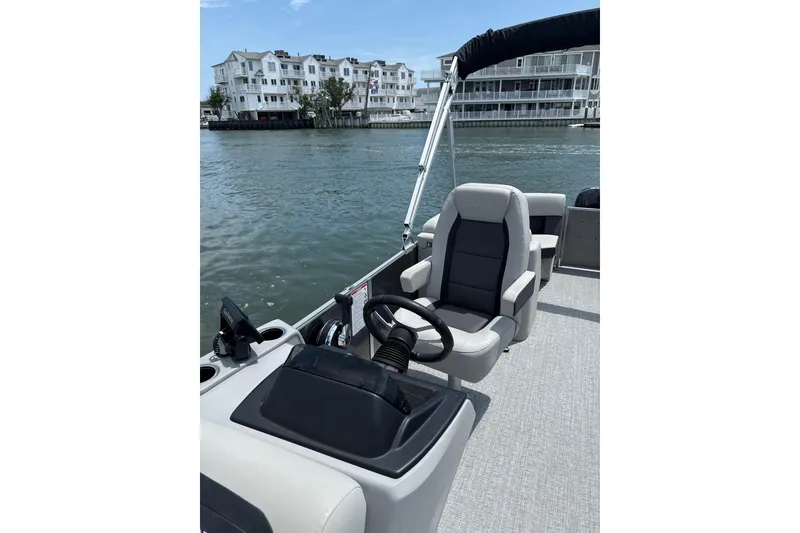Slide: The Image of 2025 Harris Cruiser 230 boat interior with steering wheel, overlooking waterfront buildings. - 6