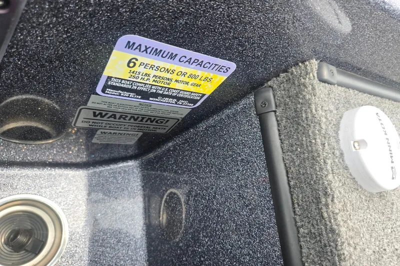 Slide: The Image of 2021 Phoenix 920 Elite boat capacity label, warning signs, and carpeted interior detail. - 12