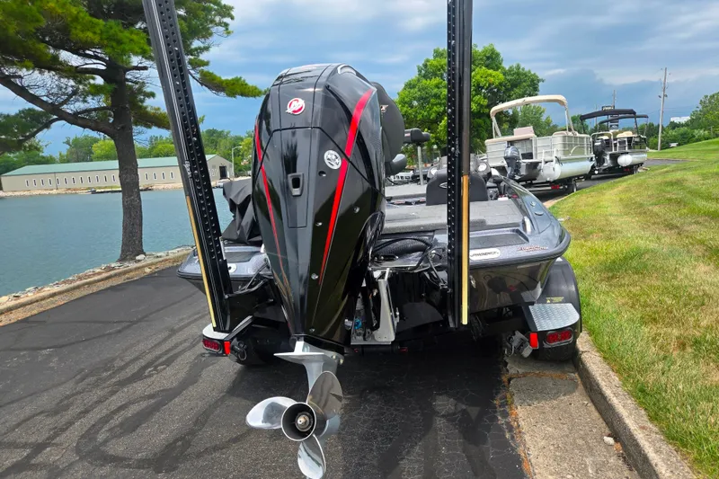 Slide: The Image of 2021 Phoenix 920 Elite boat with powerful outboard motor, parked near a scenic waterfront. - 2
