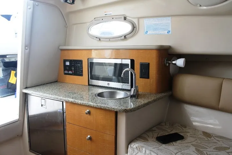 Slide: The Image of 2006 Robalo R265 Walkaround cabin with kitchenette, featuring microwave, sink, and seating area. - 12