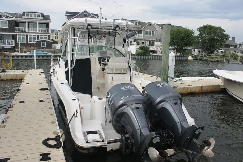 Slide: The Image of 2006 Robalo R265 Walkaround boat docked with twin engines, residential backdrop. - 1