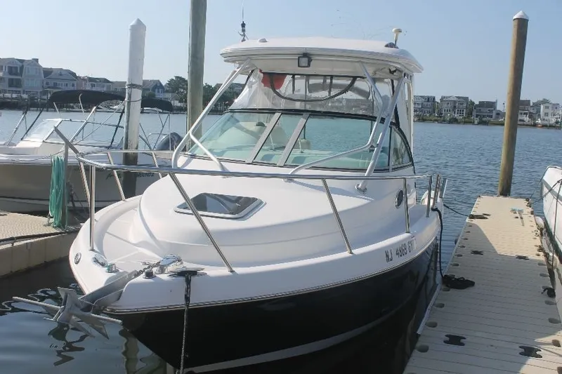 Slide: The Image of 2006 Robalo R265 Walkaround boat docked at marina, clear sky, waterfront homes in background. - 2