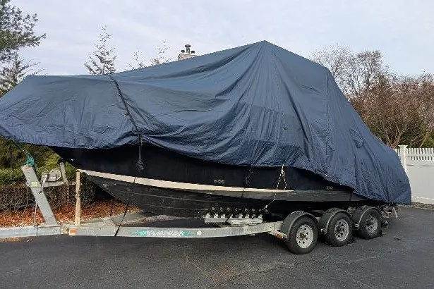 Slide: The Image of 2006 Robalo R265 Walkaround boat covered on a trailer in a driveway. - 6