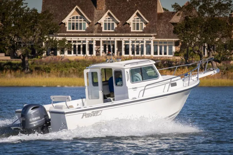 The Image of Manufacturer Provided Image: 2025 Parker 2120 Sport Cabin boat cruising on water near a large house. - 1