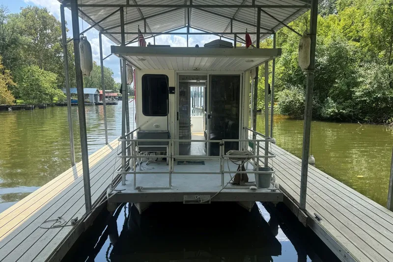 Slide: The Image of 2011 Catamaran Cruisers Lil Hobo 31 houseboat docked on a serene lake. - 2