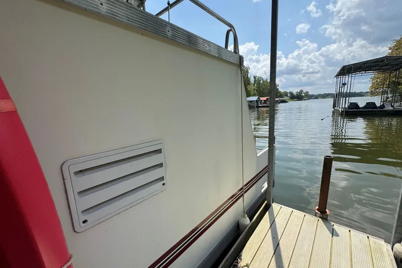 Slide: The Image of 2011 Catamaran Cruisers Lil Hobo 31 docked by a serene lake under a cloudy sky. - 8