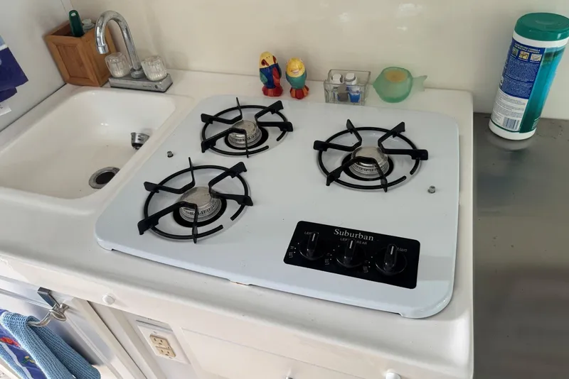 Slide: The Image of Three-burner stove and sink in 2011 Catamaran Cruisers Lil Hobo 31 kitchen area. - 27