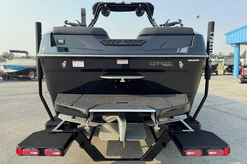 Slide: The Image of 2027 Moomba Tykon boat rear view with Raptor engine, on trailer in parking lot. - 9