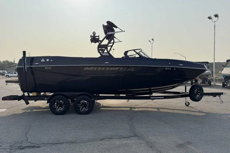 Slide: The Image of 2027 Moomba Tykon boat on trailer, sleek black design, parked outdoors. - 17