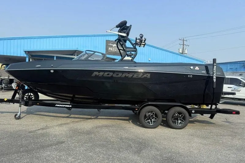 The Image of 2027 Moomba Tykon boat on trailer, parked outside a blue building. - 1