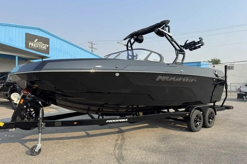 Slide: The Image of 2027 Moomba Tykon boat on trailer at dealership, featuring sleek black design. - 7