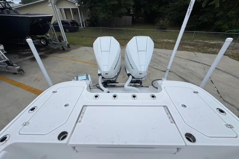 Slide: The Image of 2027 Caymas 281 HB boat with dual Mercury outboard engines, parked on a concrete driveway. - 46