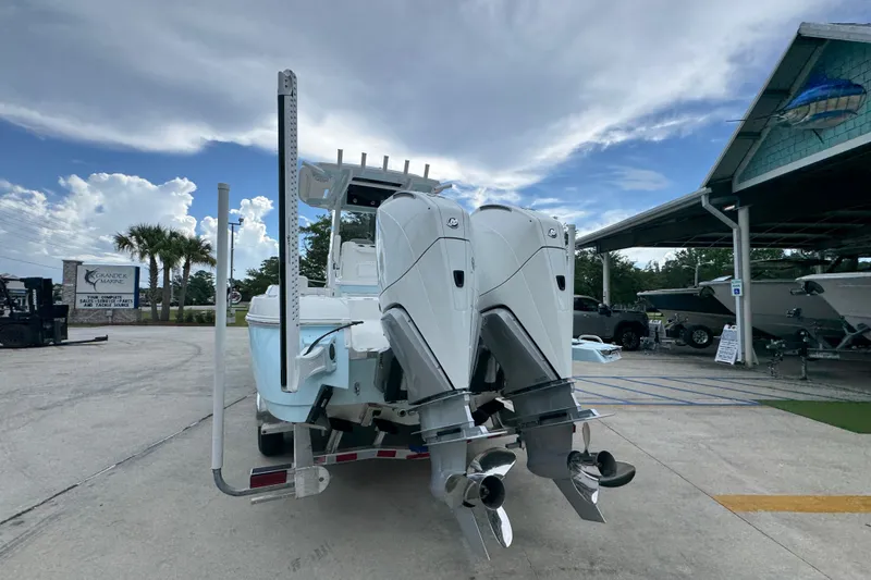 Slide: The Image of 2027 Caymas 281 HB boat with dual outboard motors at a marina under a cloudy sky. - 17