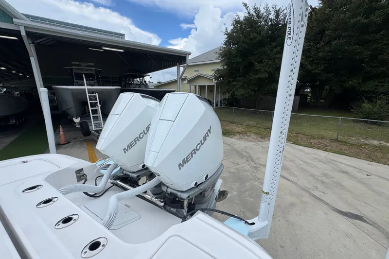 Slide: The Image of 2027 Caymas 281 HB boat with dual Mercury engines, docked near a storage facility. - 49
