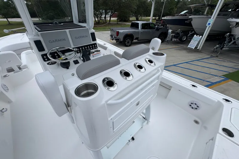 Slide: The Image of 2027 Caymas 281 HB boat cockpit with Garmin displays and seating, parked near other boats. - 41