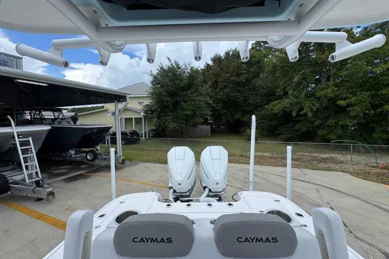 Slide: The Image of 2027 Caymas 281 HB boat with dual engines, parked outdoors near trees and buildings. - 33