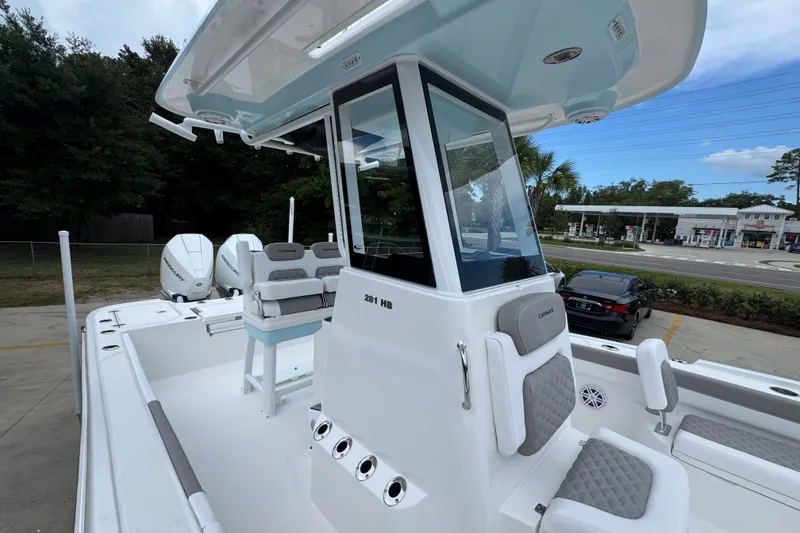 Slide: The Image of 2027 Caymas 281 HB boat with modern seating and dual outboard engines, parked outdoors. - 29