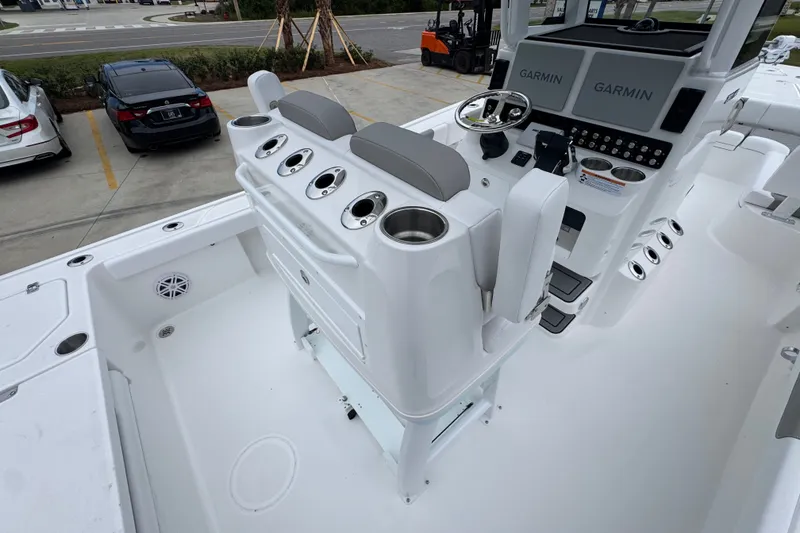 Slide: The Image of 2027 Caymas 281 HB boat interior with Garmin displays and seating, parked in a lot. - 44
