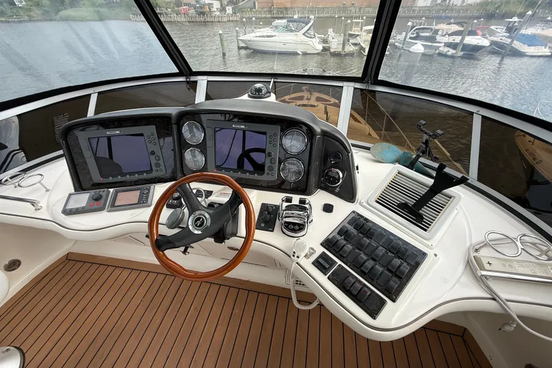 Slide: The Image of 2008 Sea Ray 44 Sedan Bridge helm with dual displays and wooden steering wheel. - 13