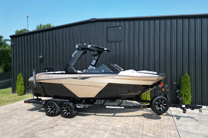 Slide: The Image of 2027 Tige Z1 boat on trailer, parked by a black metal building. - 24