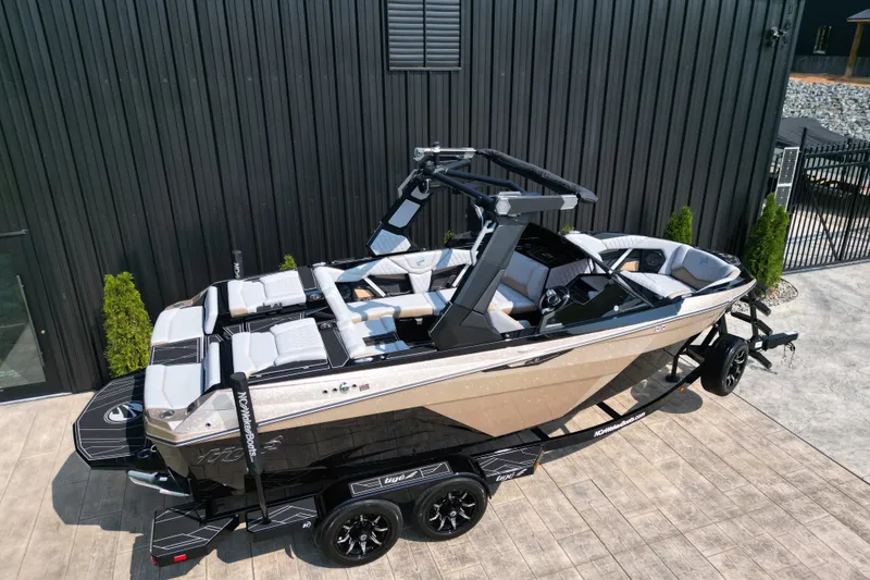 Slide: The Image of 2027 Tige Z1 boat on trailer, sleek design, parked by black building. - 20