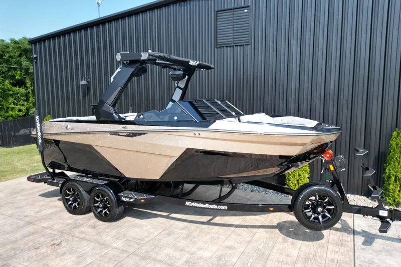 Slide: The Image of 2027 Tige Z1 boat on trailer, parked outdoors near a black metal building. - 6