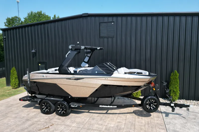 Slide: The Image of 2027 Tige Z1 boat on trailer, parked by a black building, sunny day. - 23
