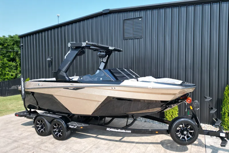 Slide: The Image of 2027 Tige Z1 boat on trailer, sleek design, parked by black building. - 5