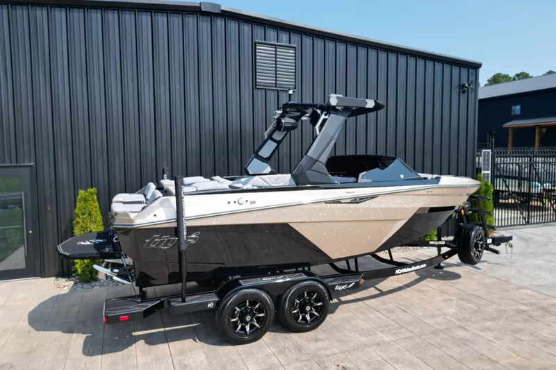 Slide: The Image of 2027 Tige Z1 boat on trailer, parked outside a modern building. - 2